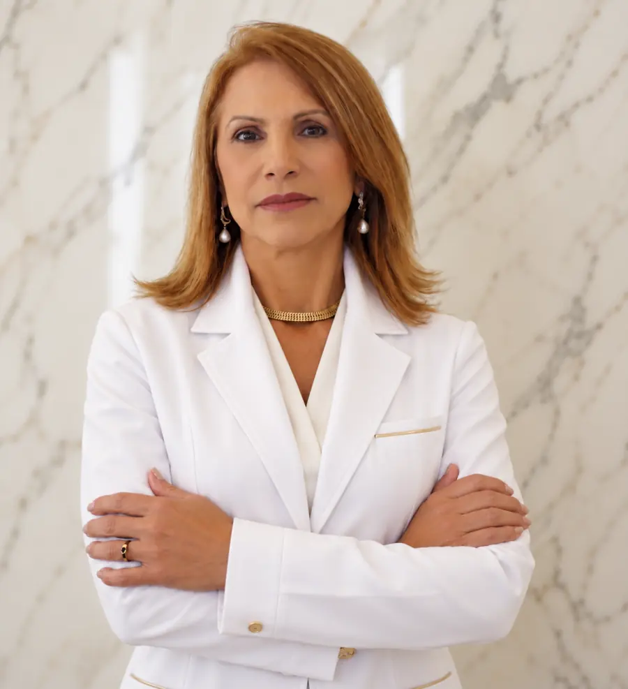 Neila Almeida, nutricionista, de jaleco e braços cruzados